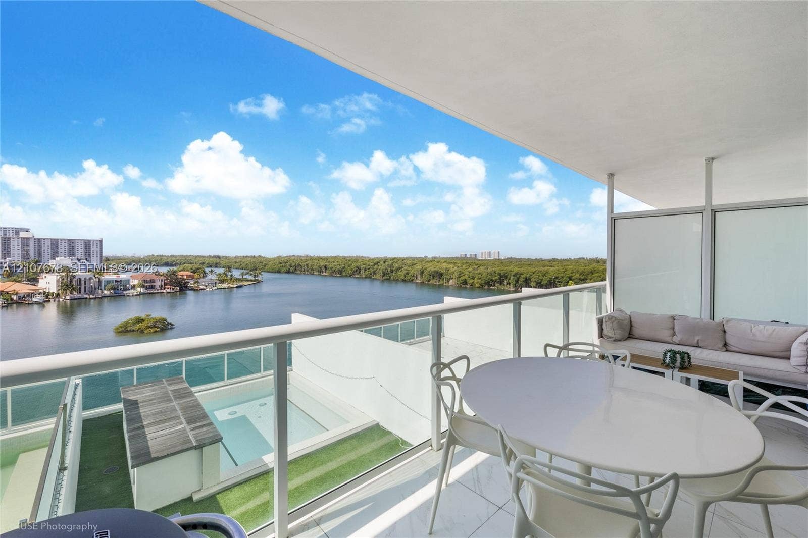 400 Sunny Isles Boulevard, #704, Sunny Isles Beach, FL 33160 Covered terrace featuring glass panel railings, white tile flooring, and direct access to an outdoor pool with integrated wood decking