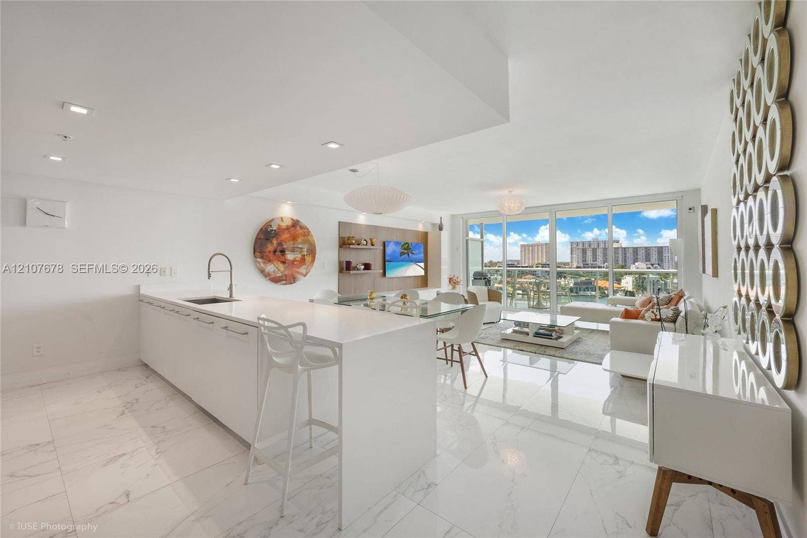 400 Sunny Isles Boulevard, #704, Sunny Isles Beach, FL 33160 Open-concept interior featuring large-format tile flooring, a kitchen island with stone-finish countertops, recessed lighting, and floor-to-ceiling glass sliding doors leading to a balcony