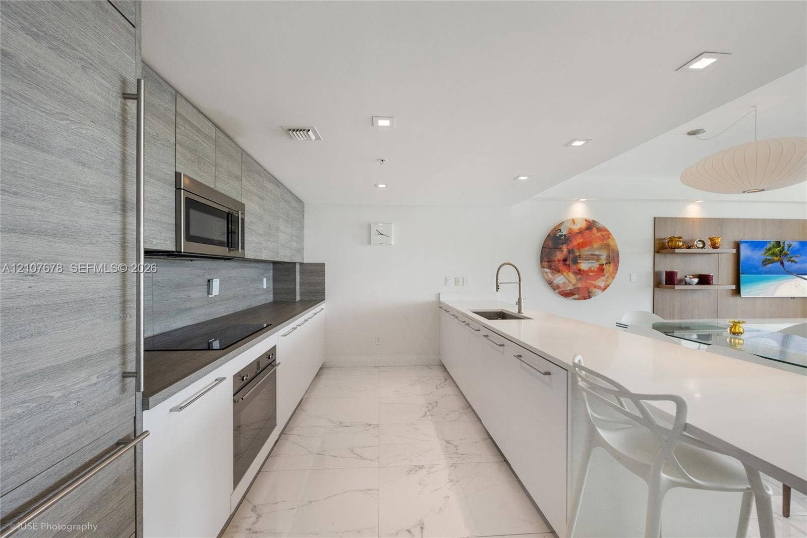 400 Sunny Isles Boulevard, #704, Sunny Isles Beach, FL 33160 Contemporary kitchen featuring floor-to-ceiling wood-finish cabinetry, solid surface countertops, integrated stainless steel appliances, and large-format tile flooring
