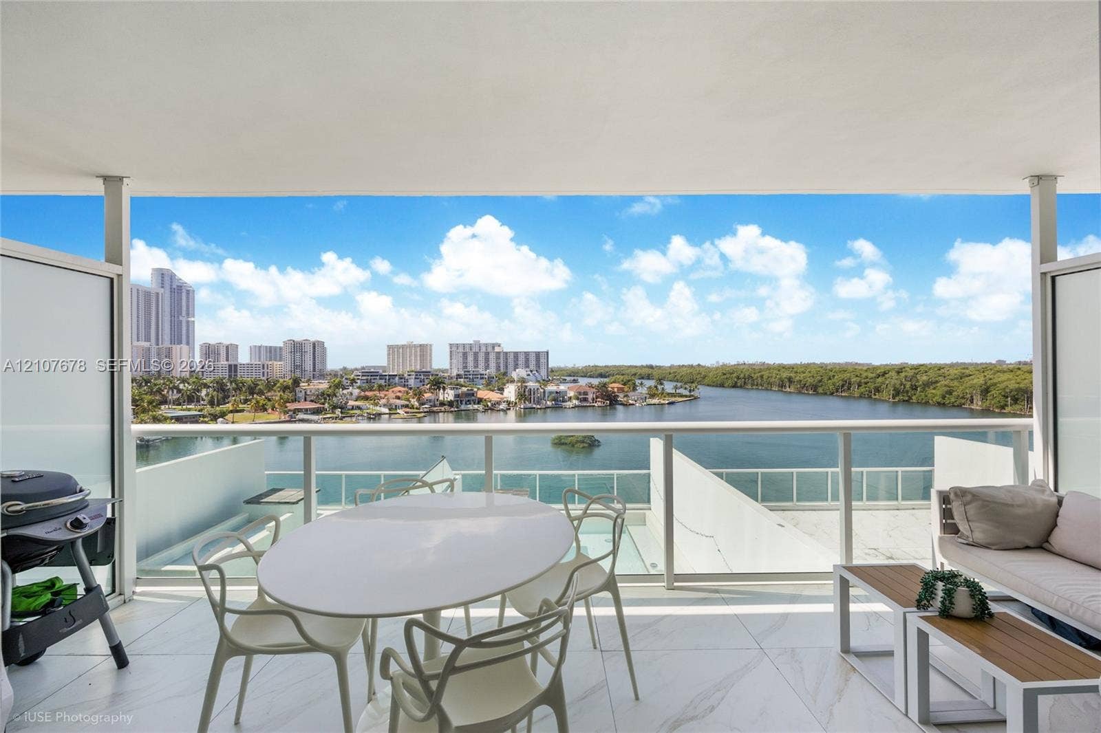 400 Sunny Isles Boulevard, #704, Sunny Isles Beach, FL 33160 Covered balcony featuring large-format stone tile flooring and a glass-paneled railing overlooking the water