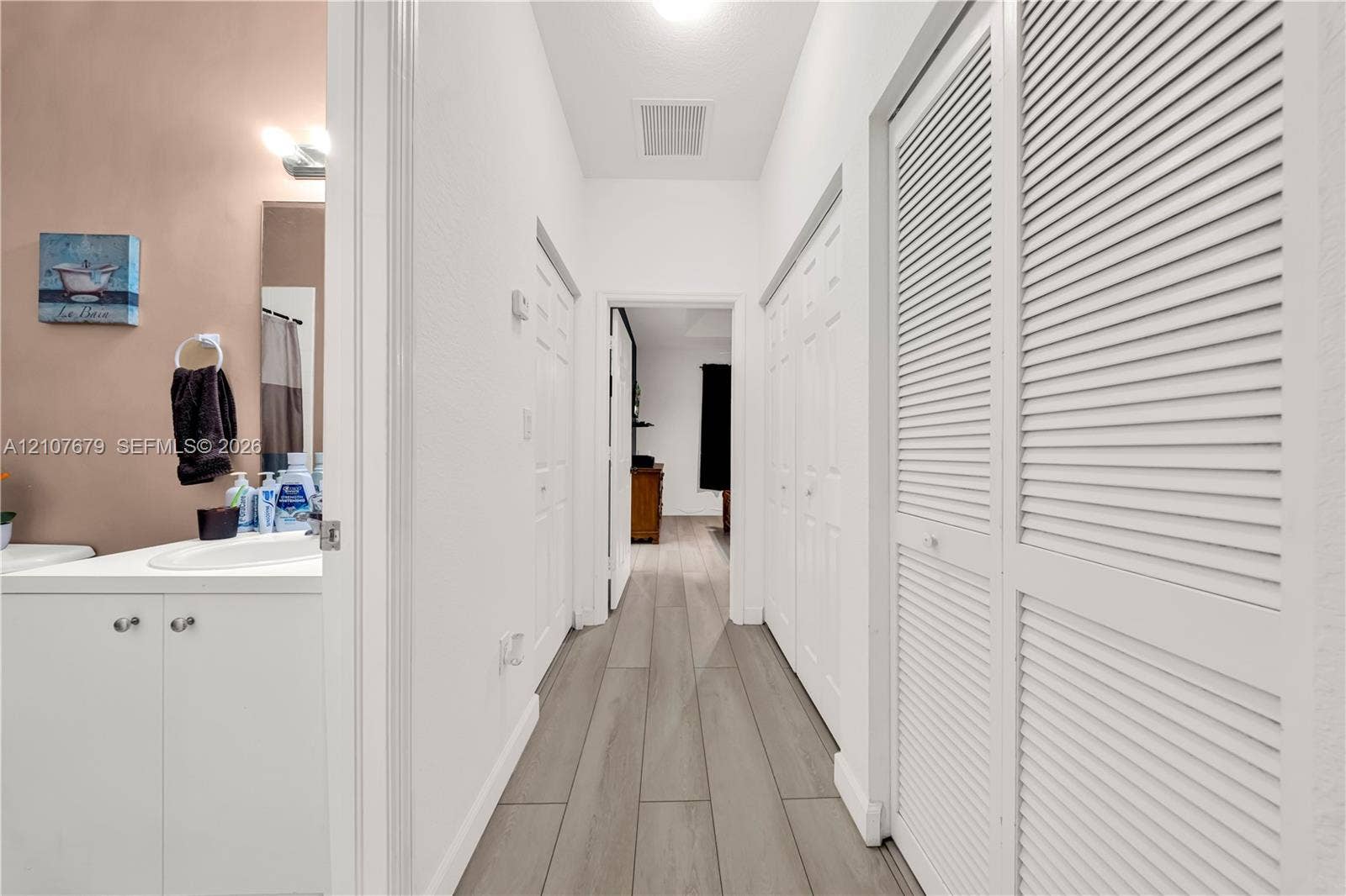 22066 SW 93rd Place, Cutler Bay, FL 33190 Wood-finish flooring, white cabinetry with integrated sink, and dual white louvered-style closet doors