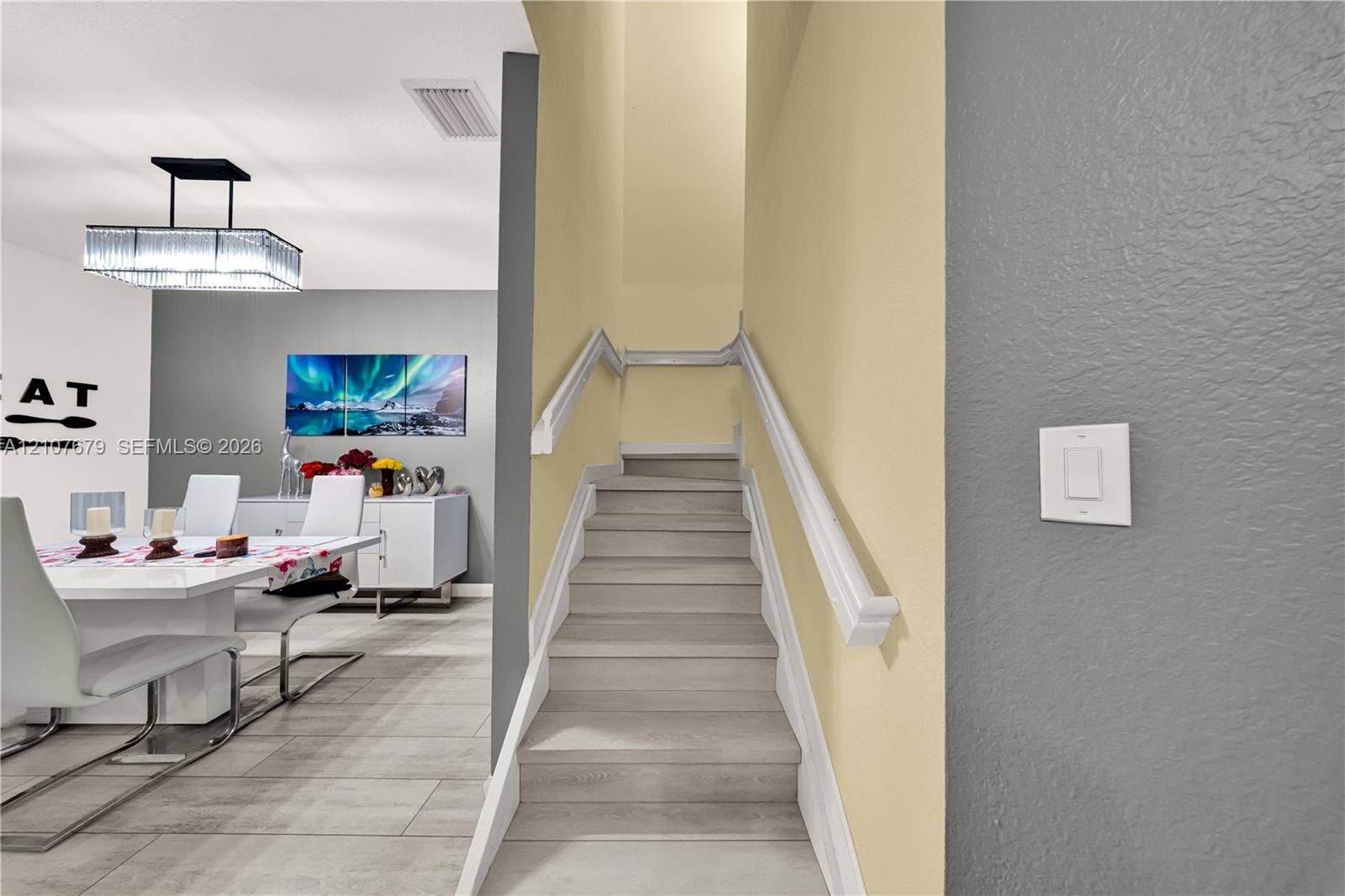 22066 SW 93rd Place, Cutler Bay, FL 33190 Staircase featuring wood-finish treads and white handrails, complemented by large-format tile flooring and a contemporary rectangular chandelier