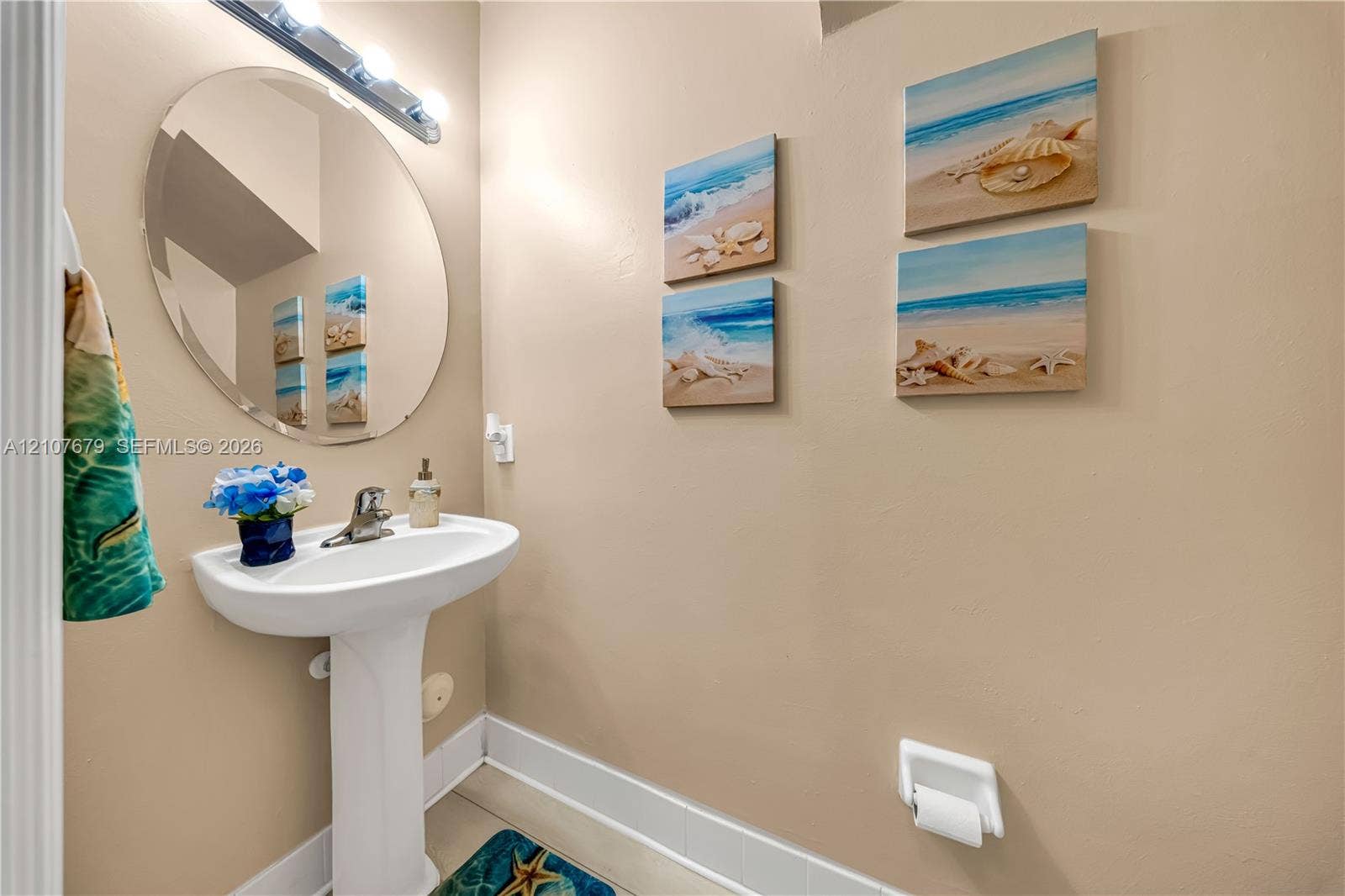 22066 SW 93rd Place, Cutler Bay, FL 33190 White pedestal sink with a chrome faucet, frameless circular wall mirror, and a wall-mounted light fixture