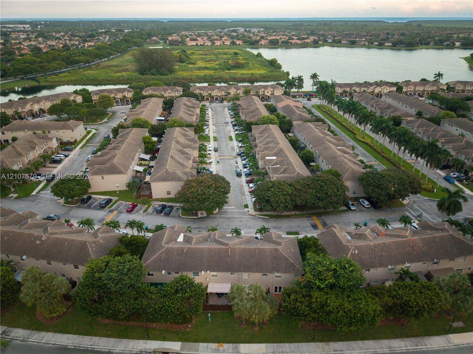 22066 SW 93rd Place, Cutler Bay, FL 33190 Aerial perspective featuring a multi-building residential complex with pitched roofs, paved streets, and expansive green space bordering a large lake