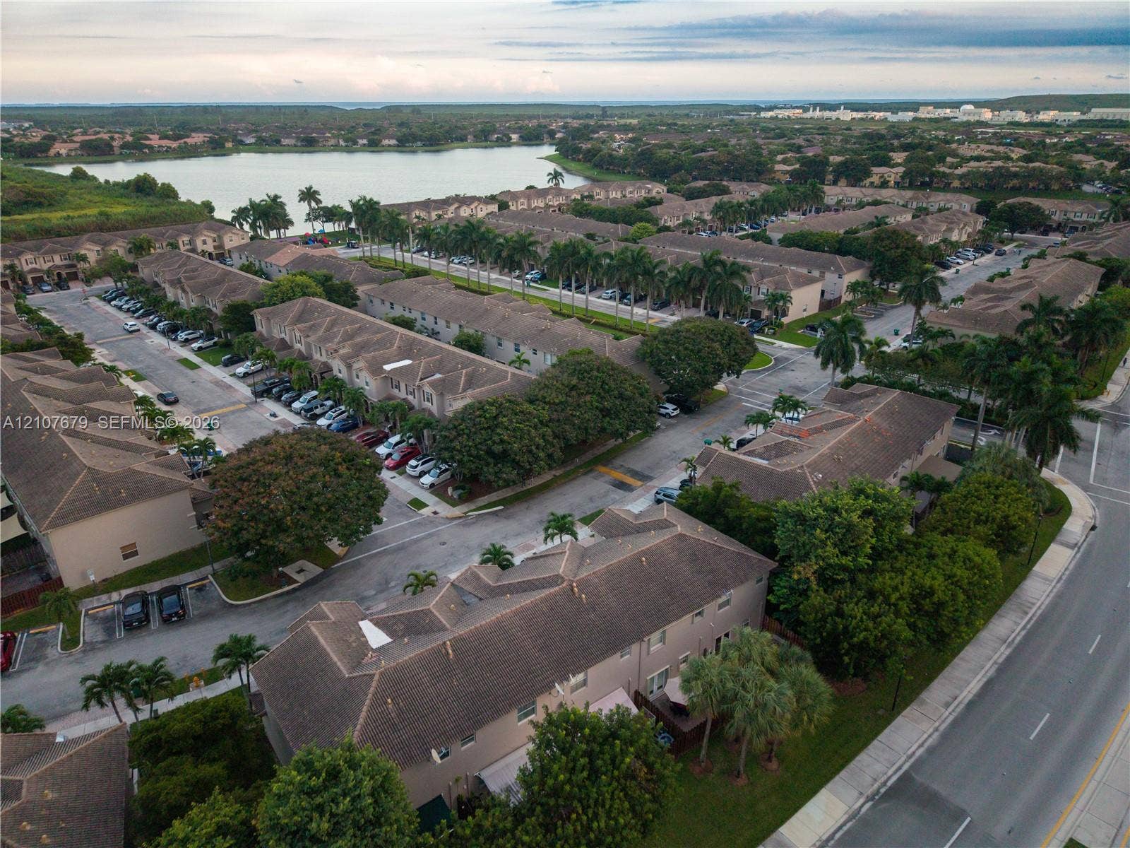 22066 SW 93rd Place, Cutler Bay, FL 33190 Aerial perspective of a multi-unit residential community featuring clay-tile roofing, established palm trees, paved thoroughfares, and proximity to a large body of water