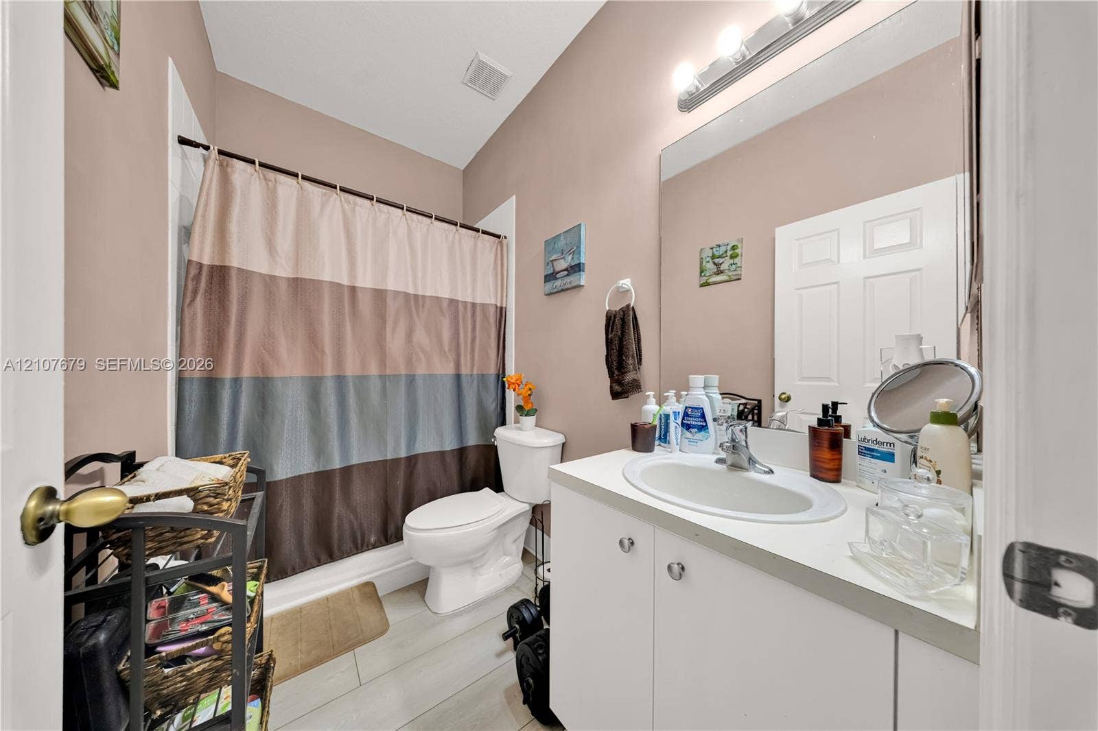 22066 SW 93rd Place, Cutler Bay, FL 33190 Bathroom featuring a white vanity cabinet with an integrated oval sink, a large wall-mounted mirror, a tub-shower combination, and wood-finish flooring