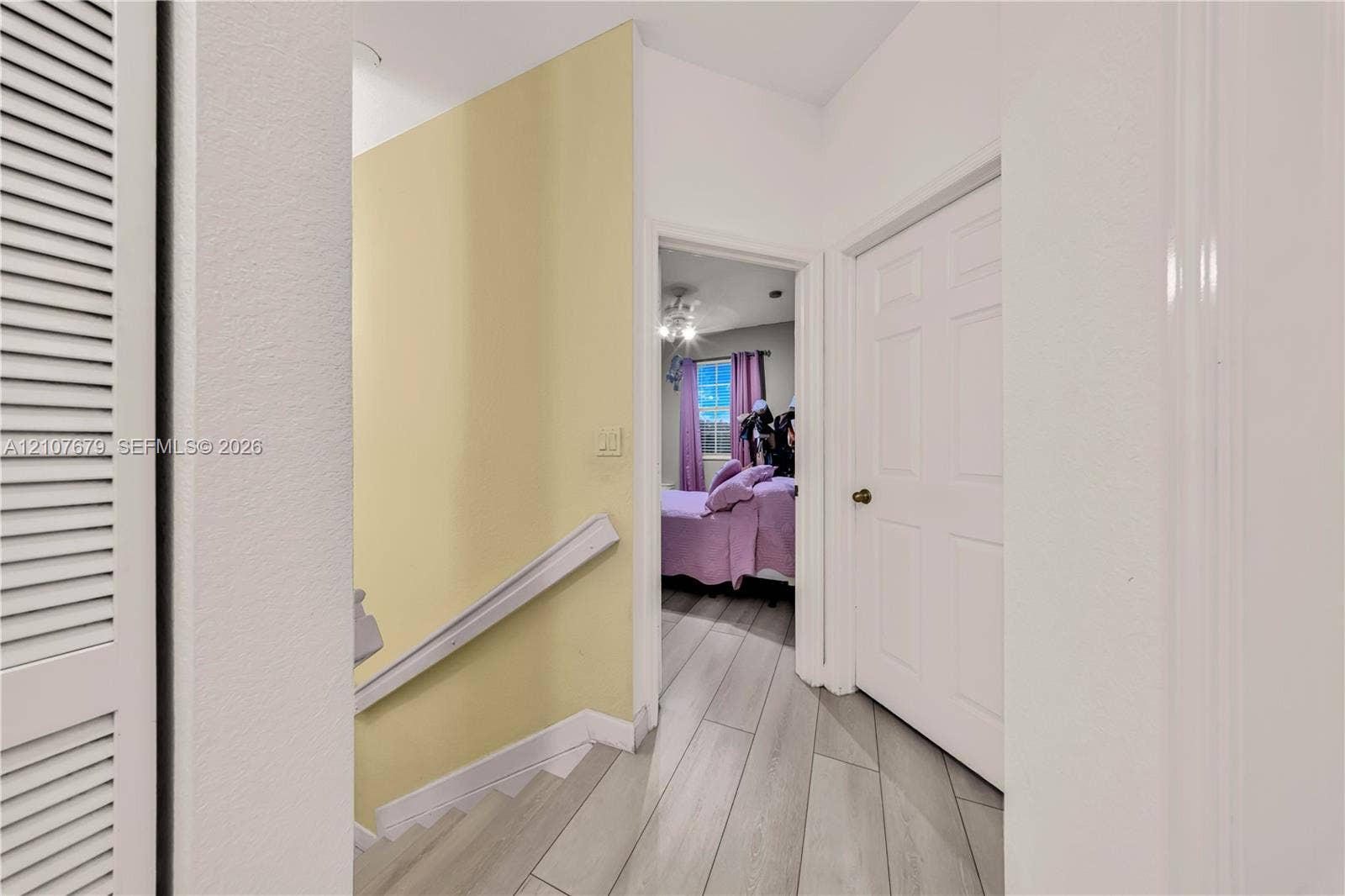 22066 SW 93rd Place, Cutler Bay, FL 33190 Hallway featuring wood-finish tile flooring, white paneled interior doors, and a louvered closet door