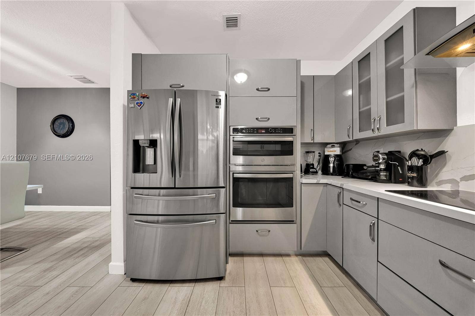 22066 SW 93rd Place, Cutler Bay, FL 33190 Kitchen featuring flat-panel gray cabinetry, stainless steel built-in double ovens, stainless steel French door refrigerator, solid surface countertops, and wood-finish flooring