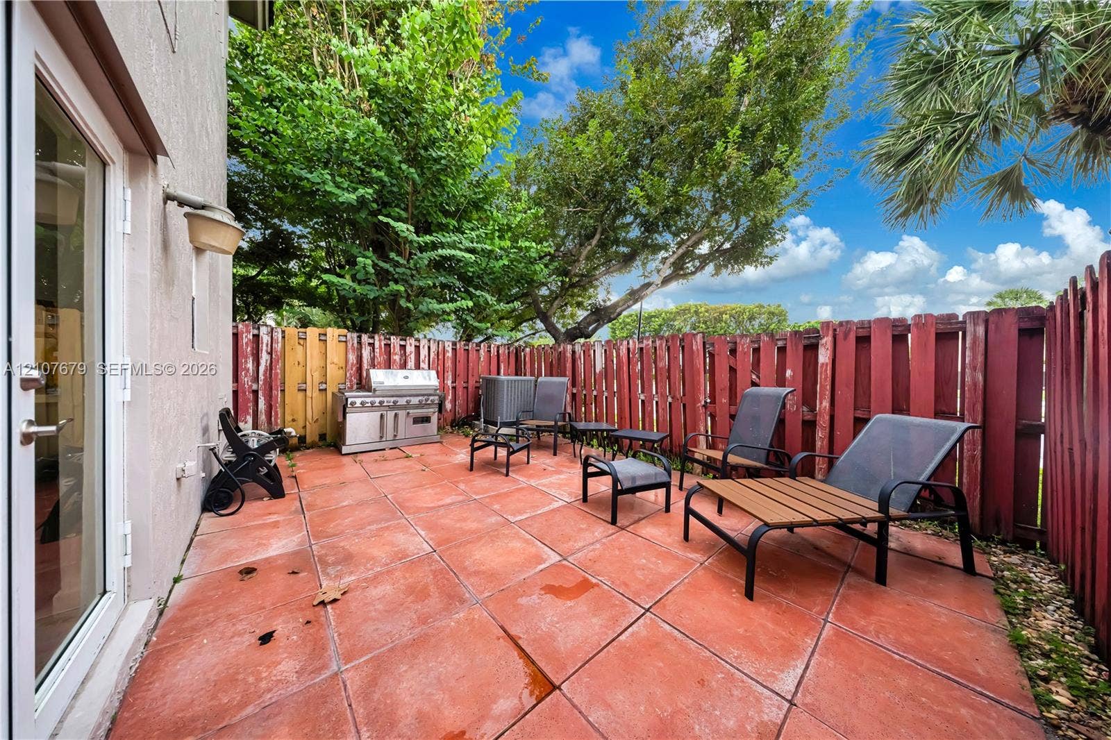 22066 SW 93rd Place, Cutler Bay, FL 33190 Enclosed patio featuring terracotta-style tile flooring, built-in stainless steel outdoor grill, and perimeter wood fencing
