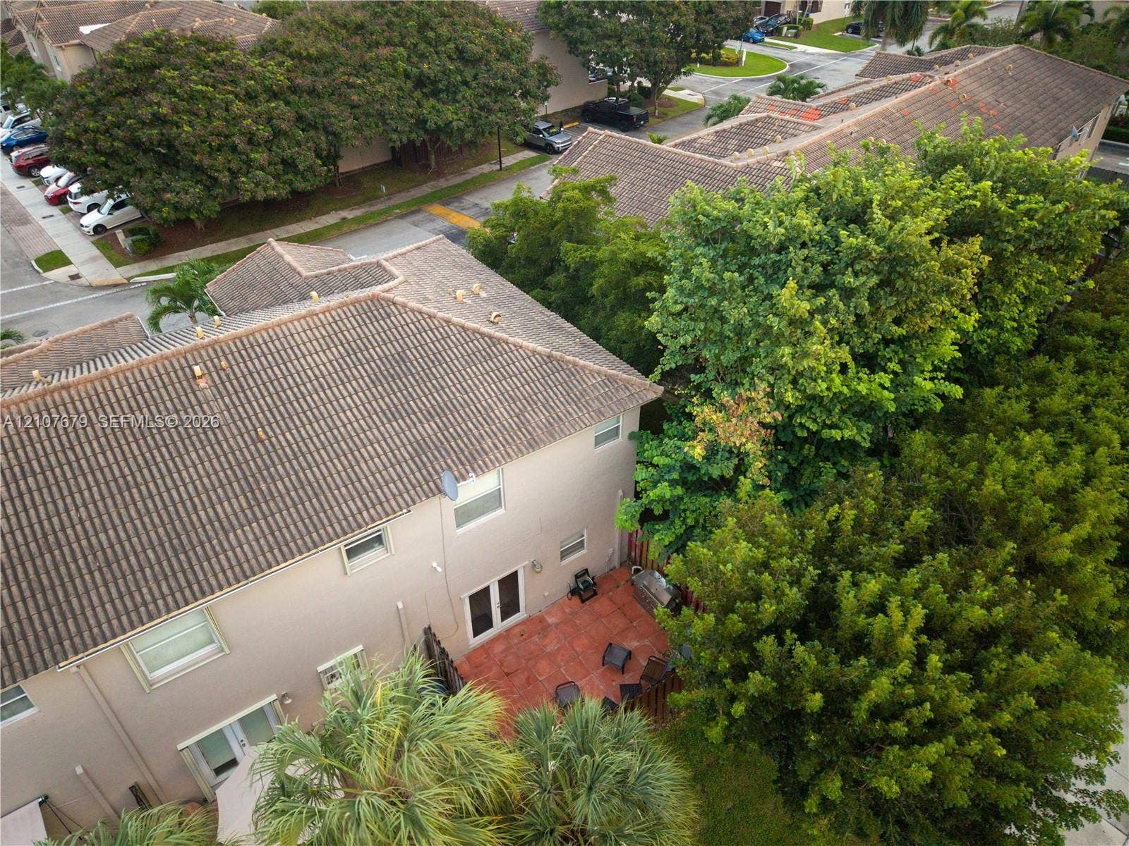 22066 SW 93rd Place, Cutler Bay, FL 33190 Aerial perspective featuring a multi-story exterior with a tiled roof, terra-cotta patio, and mature tree canopy