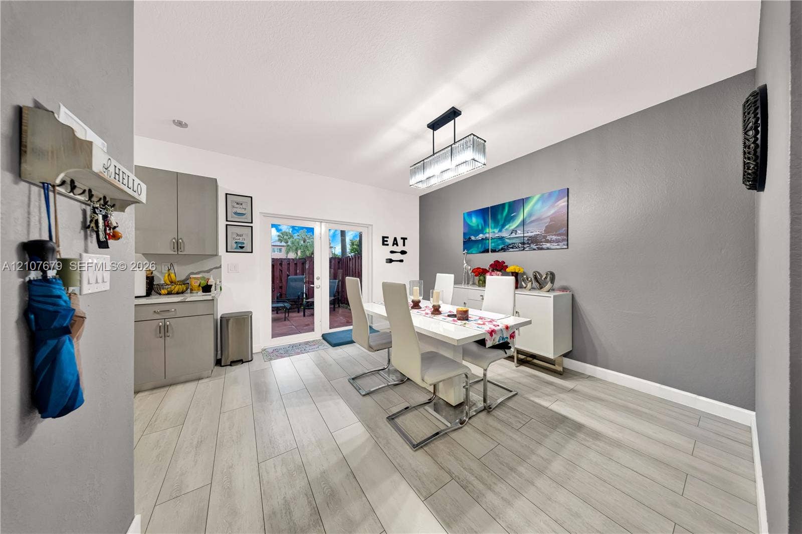 22066 SW 93rd Place, Cutler Bay, FL 33190 Dining area featuring wood-finish tile flooring, grey cabinetry with solid-surface countertops, dual glass-paned doors, and a rectangular multi-light pendant fixture