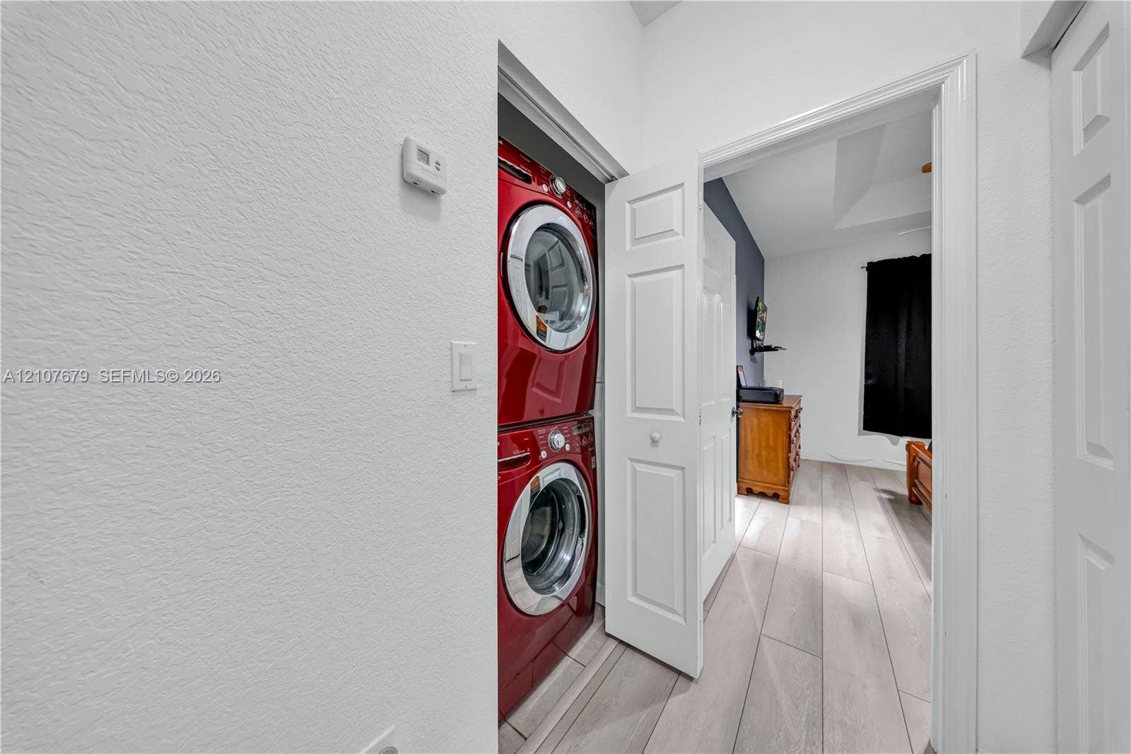 22066 SW 93rd Place, Cutler Bay, FL 33190 Laundry closet featuring a stacked washer and dryer unit, wood-finish flooring, and multi-panel interior doors