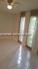 6310 SW 79th Street, #12, South Miami, South Miami, FL 33143 Neutral-toned tile flooring, dual floor-to-ceiling windows, and a ceiling-mounted light fixture with a fan