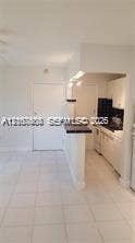 6310 SW 79th Street, #12, South Miami, South Miami, FL 33143 Kitchen featuring white cabinetry, dark contrasting countertops, a breakfast bar, and light-toned tile flooring