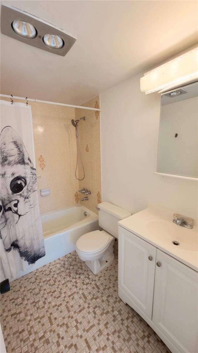 701 NE 1st Court, #202, Hallandale Beach, Hallandale Beach, FL 33009 Bathroom featuring a white vanity cabinet with a molded sink basin, wall-mounted mirror, ceiling-mounted heating unit, and patterned tile flooring