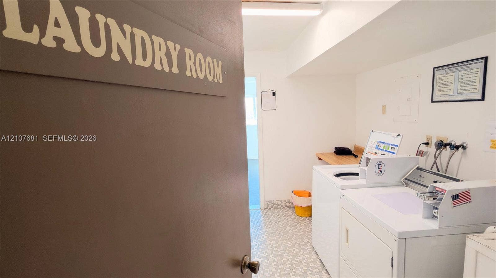 701 NE 1st Court, #202, Hallandale Beach, Hallandale Beach, FL 33009 Laundry room featuring patterned resilient flooring, overhead lighting, and a built-in wooden folding counter