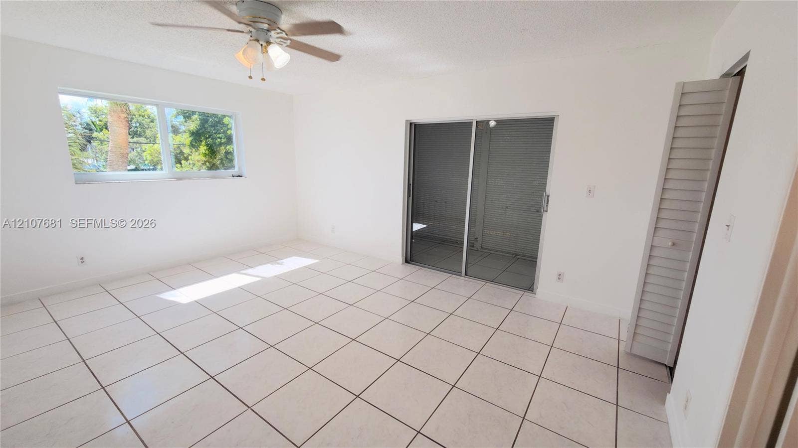701 NE 1st Court, #202, Hallandale Beach, Hallandale Beach, FL 33009 Ceramic tile flooring, sliding glass door, ceiling fan with integrated lighting, and louvered closet doors