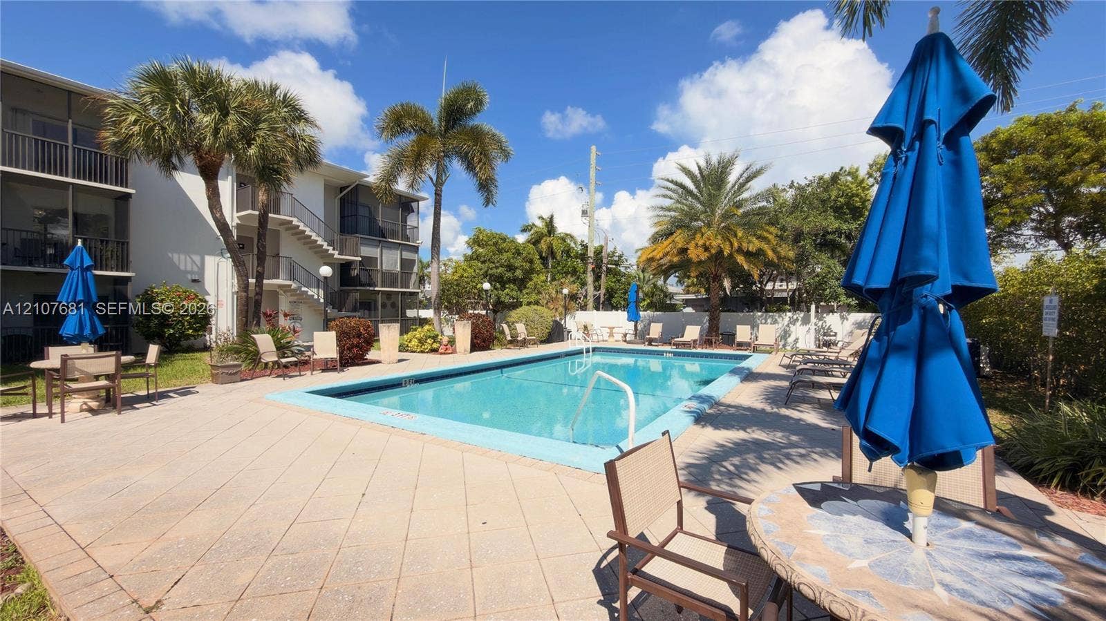 701 NE 1st Court, #202, Hallandale Beach, Hallandale Beach, FL 33009 Rectangular in-ground pool with a surrounding paved deck, palm trees, and perimeter landscaping
