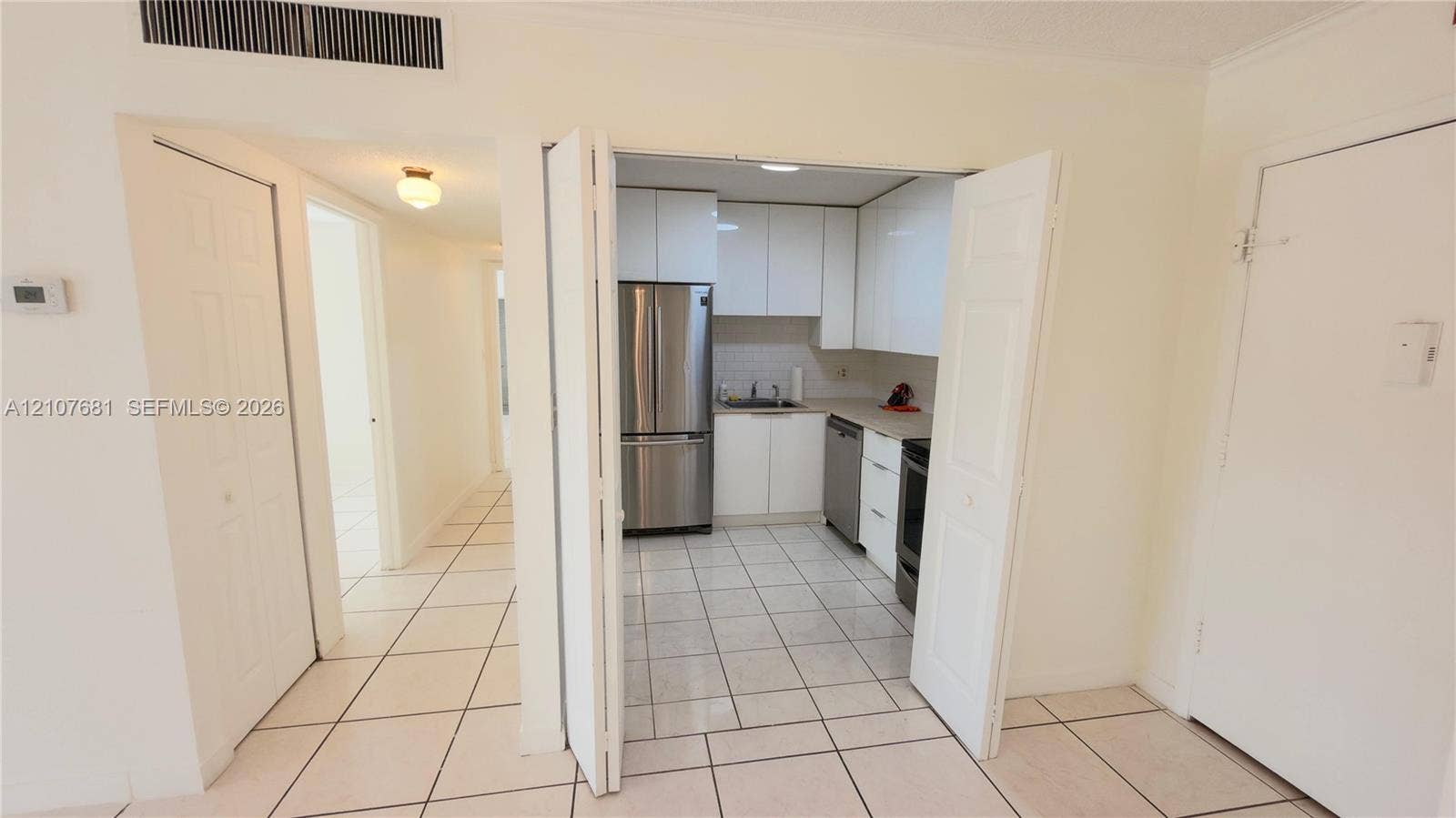 701 NE 1st Court, #202, Hallandale Beach, Hallandale Beach, FL 33009 Kitchen featuring high-gloss white cabinetry, stainless steel appliances, ceramic tile flooring, and solid-surface countertops