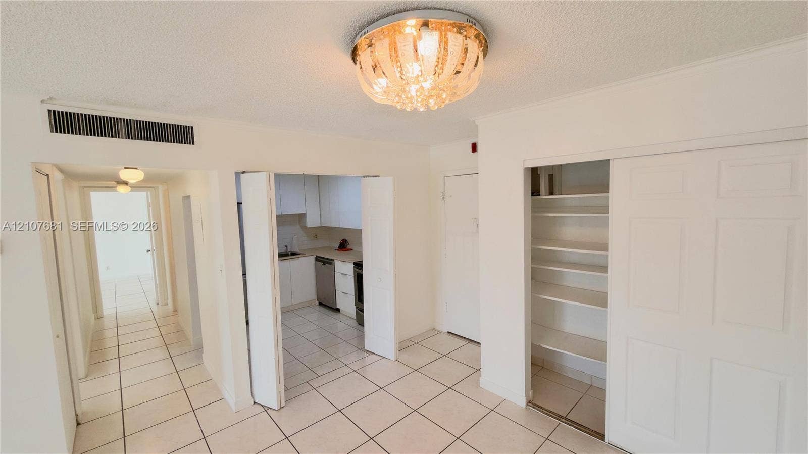 701 NE 1st Court, #202, Hallandale Beach, Hallandale Beach, FL 33009 Interior space featuring polished ceramic tile flooring, built-in recessed pantry cabinetry with folding doors, and a decorative flush-mount ceiling light fixture