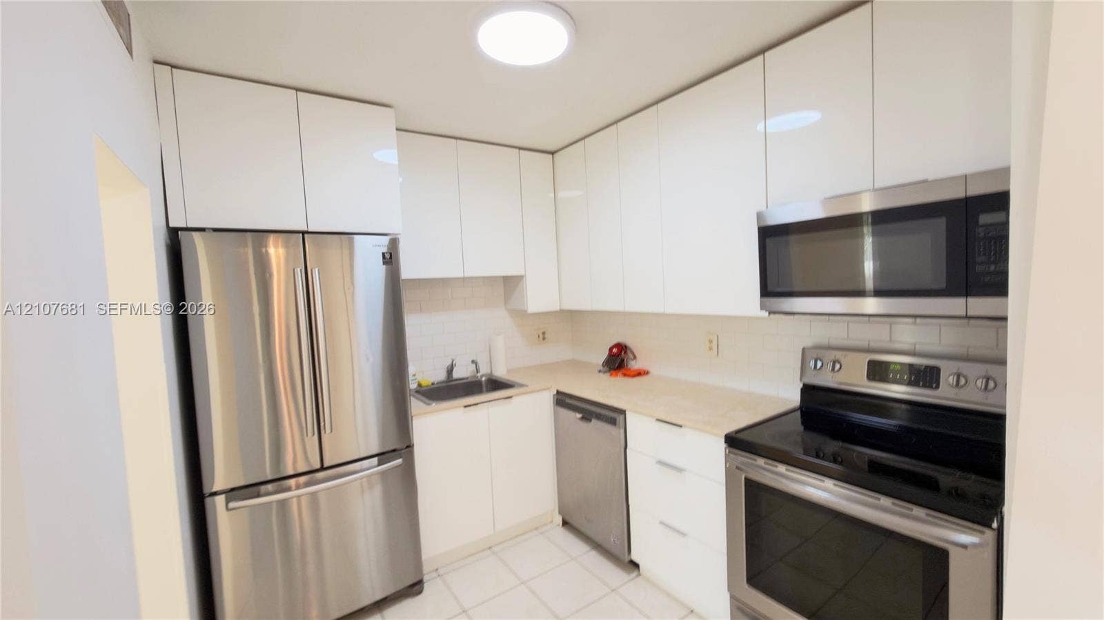 701 NE 1st Court, #202, Hallandale Beach, Hallandale Beach, FL 33009 Kitchen featuring high-gloss white cabinetry, stainless steel appliances, light-toned countertops, subway tile backsplash, and tile flooring