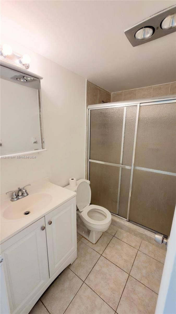 701 NE 1st Court, #202, Hallandale Beach, Hallandale Beach, FL 33009 Bathroom featuring white shaker-style cabinetry, an integrated sink with polished chrome hardware, tiled flooring, and a walk-in shower with sliding glass doors