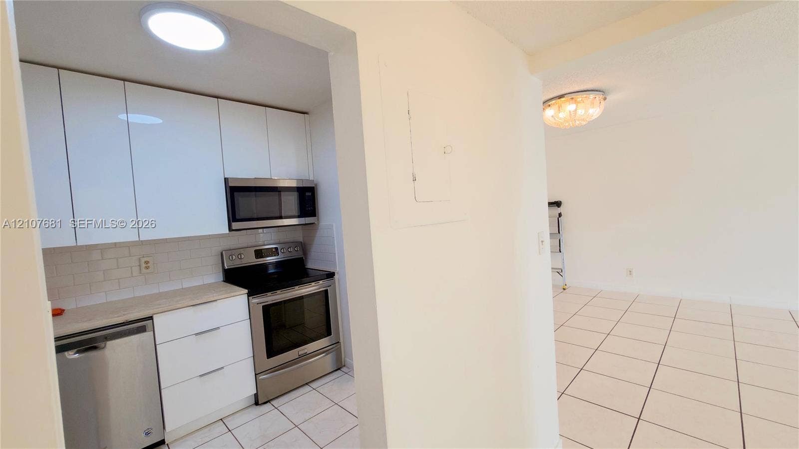 701 NE 1st Court, #202, Hallandale Beach, Hallandale Beach, FL 33009 Kitchen featuring white flat-panel cabinetry, light-toned countertops, subway tile backsplash, and stainless steel appliances, including an over-the-range microwave and electric range