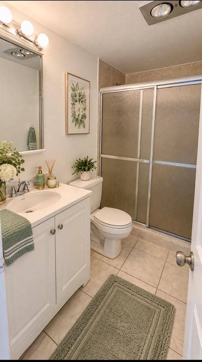 701 NE 1st Court, #202, Hallandale Beach, Hallandale Beach, FL 33009 Bathroom featuring a white vanity cabinet with a solid surface countertop, an oval undermount sink, a chrome faucet, a shower enclosure with sliding glass doors, and tiled flooring