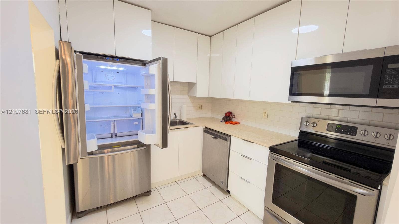701 NE 1st Court, #202, Hallandale Beach, Hallandale Beach, FL 33009 Kitchen featuring flat-panel white cabinetry, stainless steel appliances, light-toned countertops, subway tile backsplash, and tile flooring
