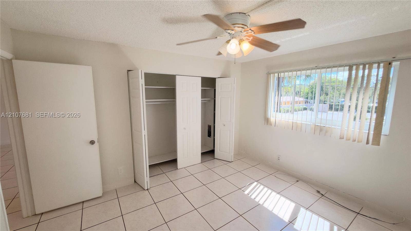701 NE 1st Court, #202, Hallandale Beach, Hallandale Beach, FL 33009 Light-filled room featuring large-format tile flooring, a multi-panel closet with built-in shelving, and a ceiling fan with integrated lighting
