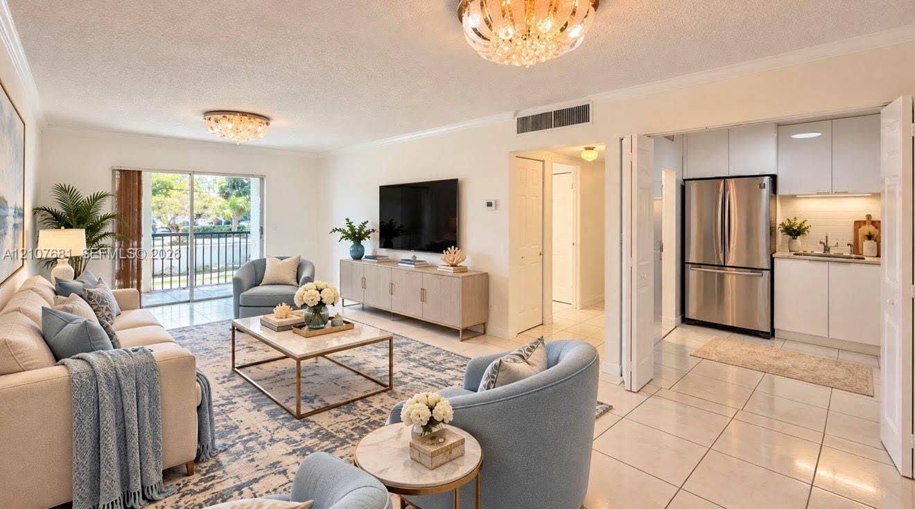 701 NE 1st Court, #202, Hallandale Beach, Hallandale Beach, FL 33009 Open-concept floor plan featuring large-format tile flooring, recessed kitchen cabinetry with a clean finish, stainless steel refrigerator, and glass sliding doors leading to an exterior balcony