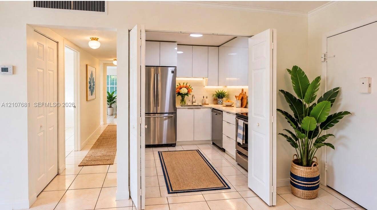 701 NE 1st Court, #202, Hallandale Beach, Hallandale Beach, FL 33009 Kitchen featuring white flat-panel cabinetry, stainless steel appliances, solid-surface countertops, under-cabinet lighting, and tile flooring