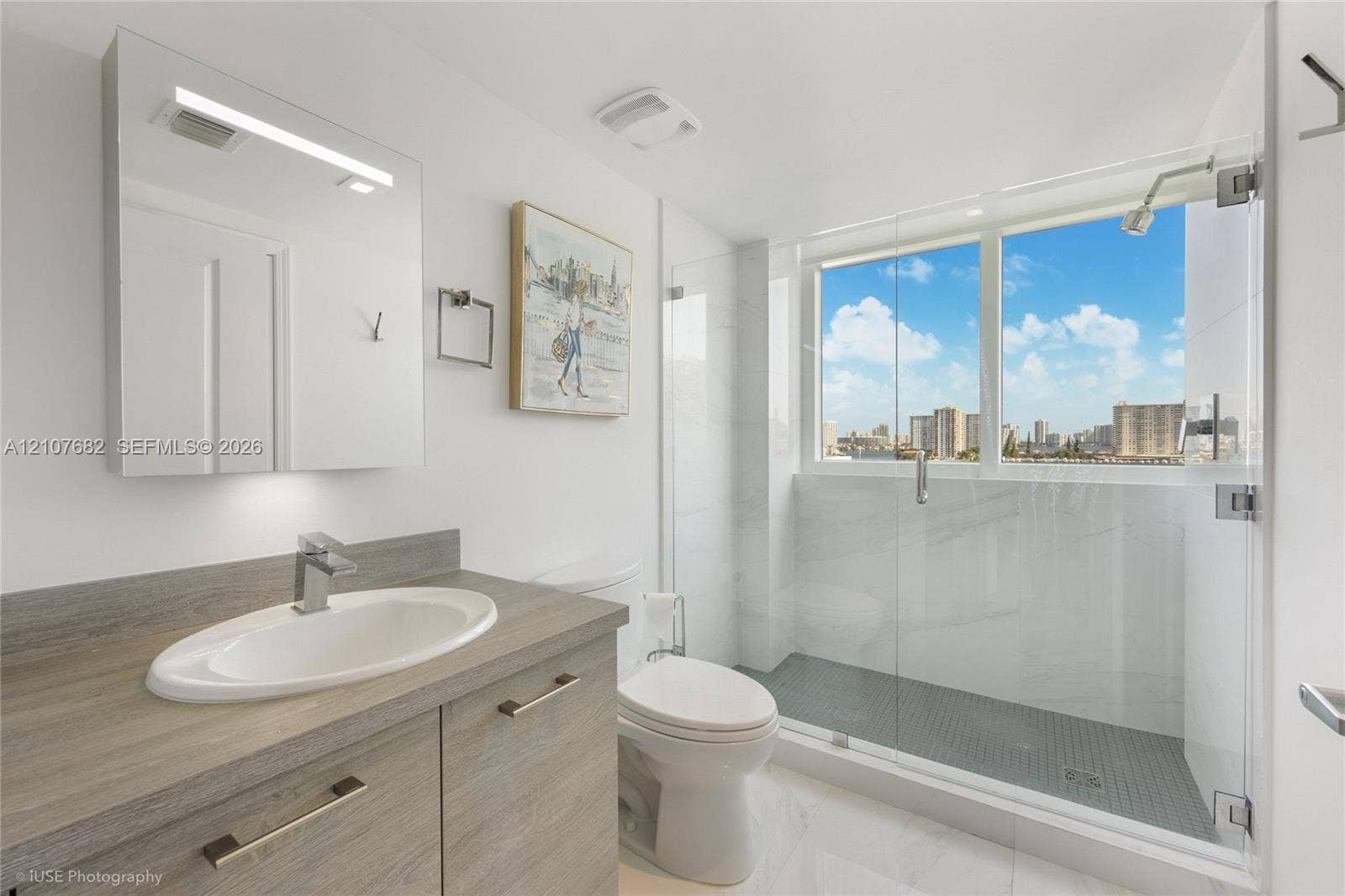 400 Sunny Isles Boulevard, #704, Sunny Isles Beach, Sunny Isles Beach, FL 33160 Bathroom featuring a wood-finish vanity with an integrated oval sink, glass-enclosed shower with tiled surround, and large-scale window
