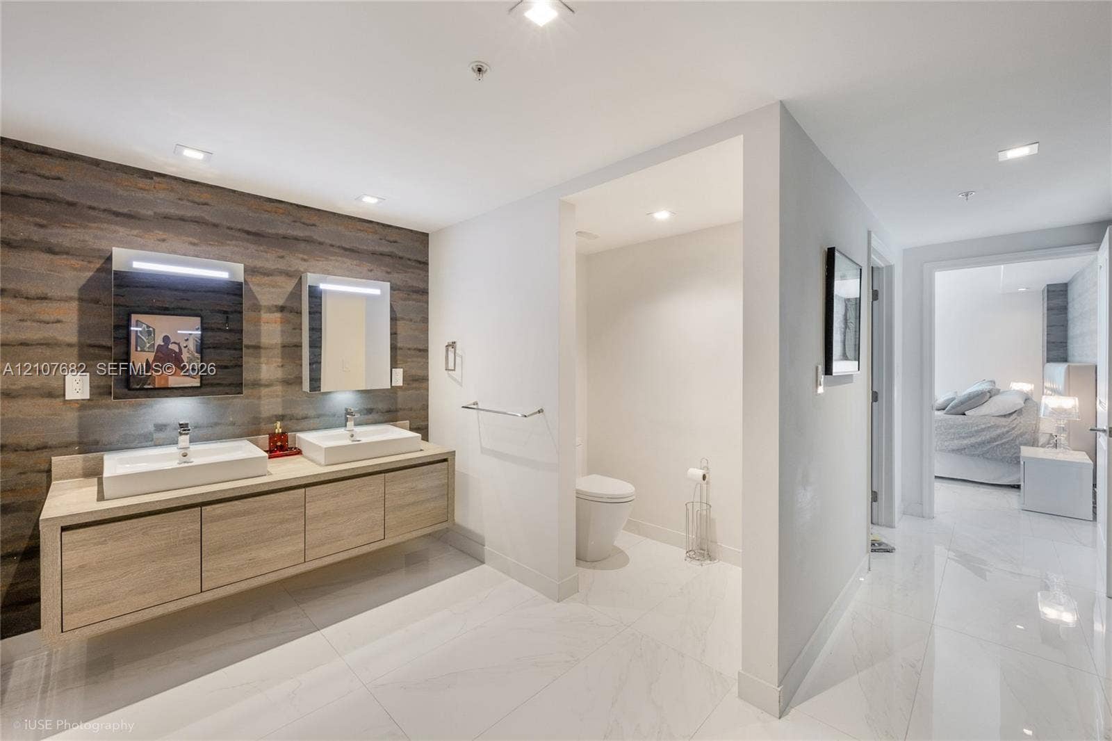 400 Sunny Isles Boulevard, #704, Sunny Isles Beach, Sunny Isles Beach, FL 33160 Floating dual-sink vanity with light wood-finish cabinetry, white rectangular vessel sinks, textured wood-panel accent wall, and polished stone-finish floor tiling