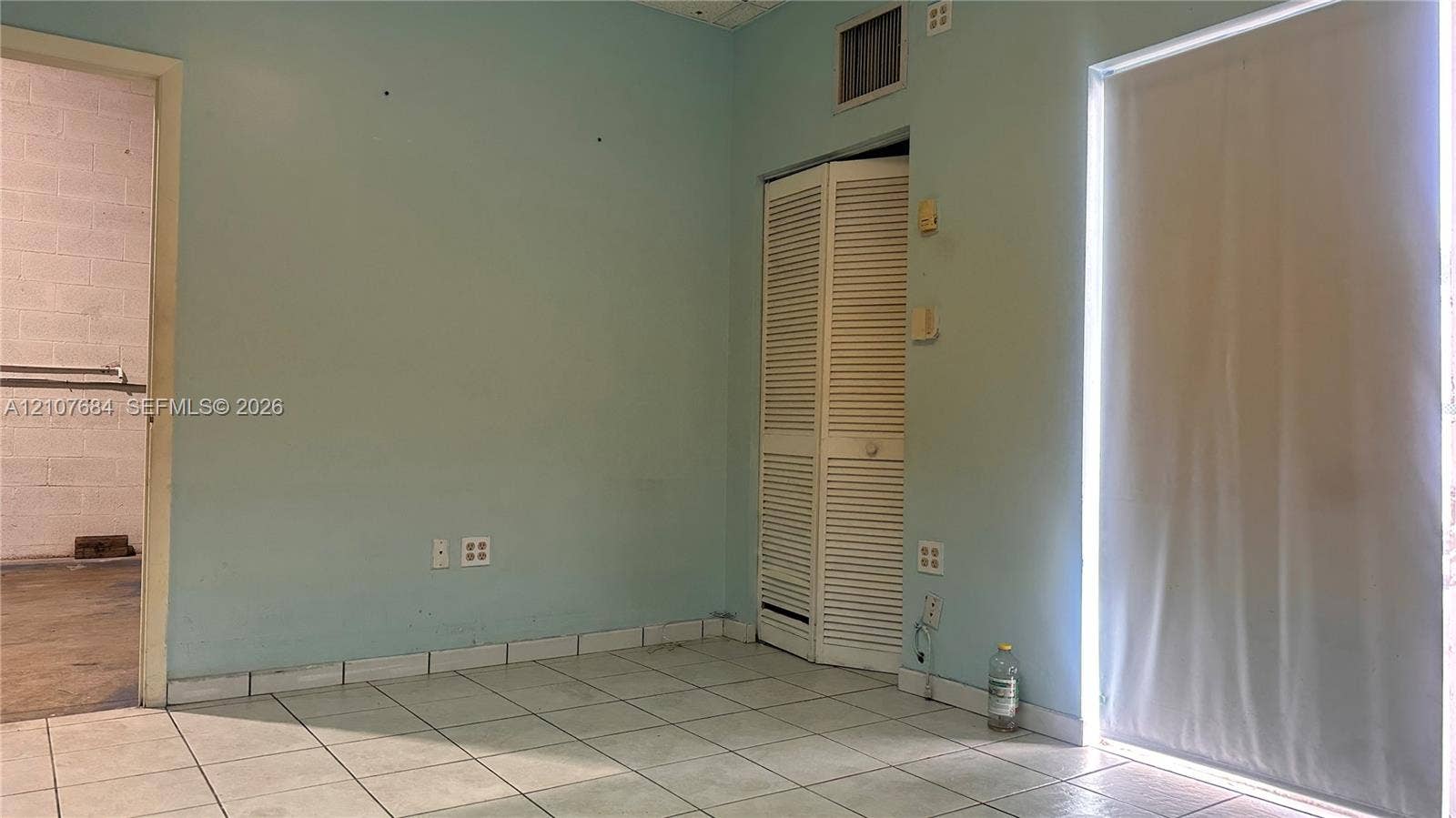 Ceramic tile flooring, bi-fold louvered closet doors, and a glass-panel door