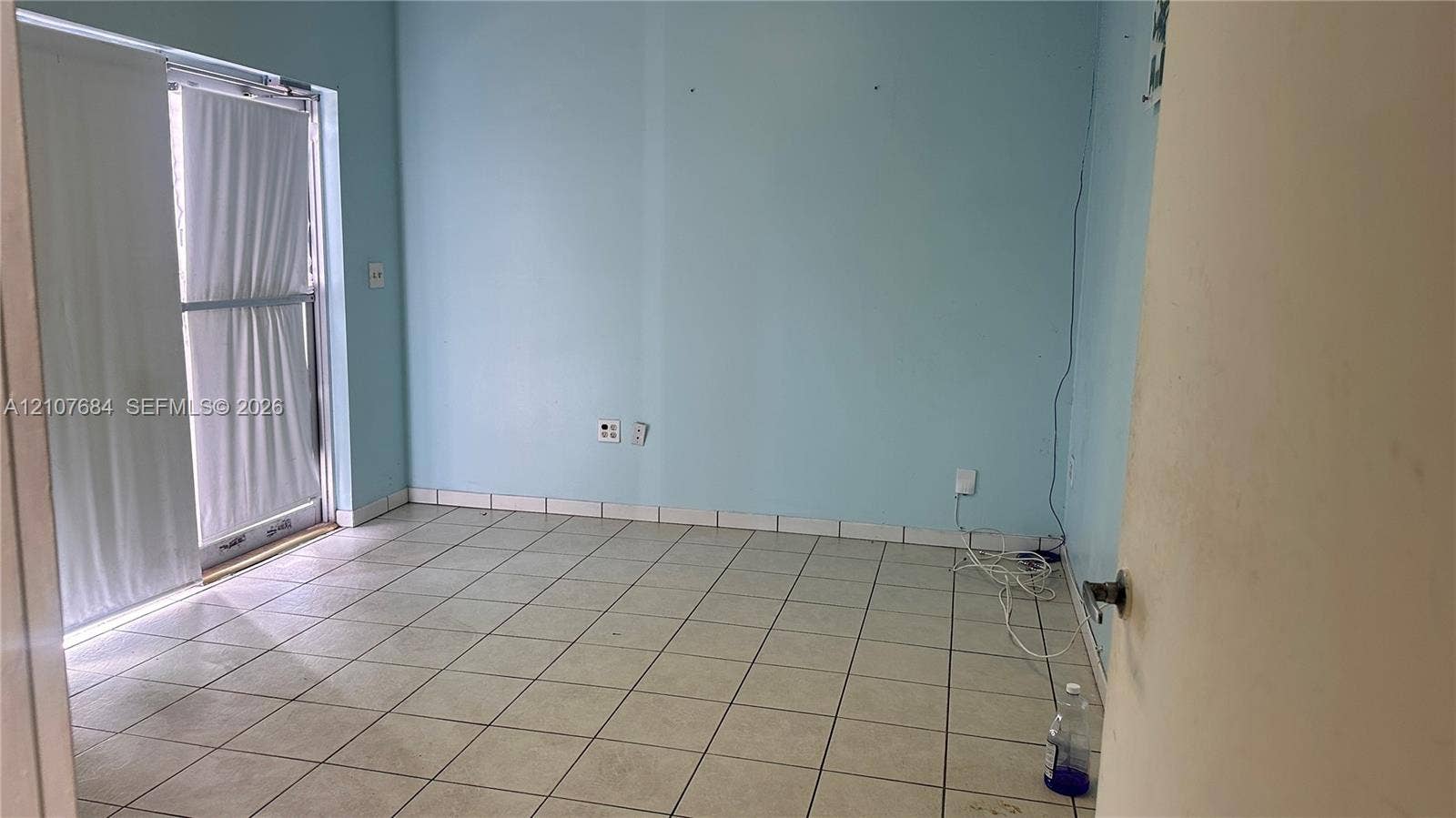 Interior space featuring neutral tile flooring and a sliding glass door providing external access