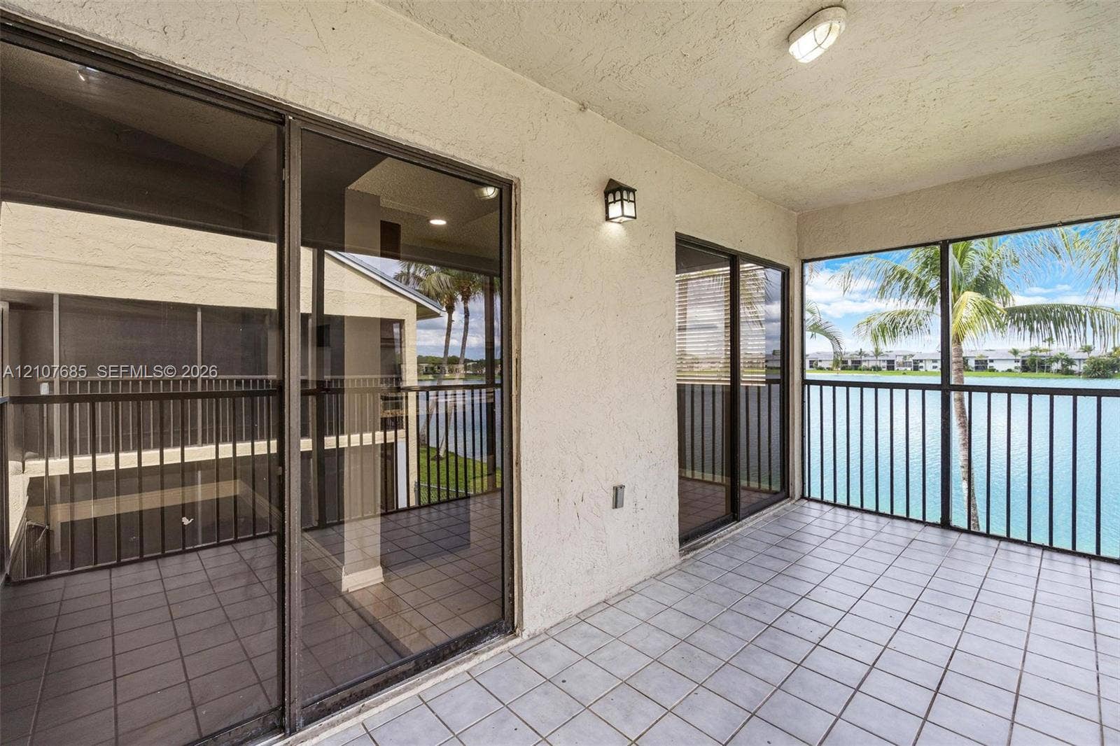 1460 Jefferson Drive, #1460L, Homestead, FL 33034 Covered balcony featuring tile flooring, sliding glass doors, screen enclosure, and metal railings overlooking the water
