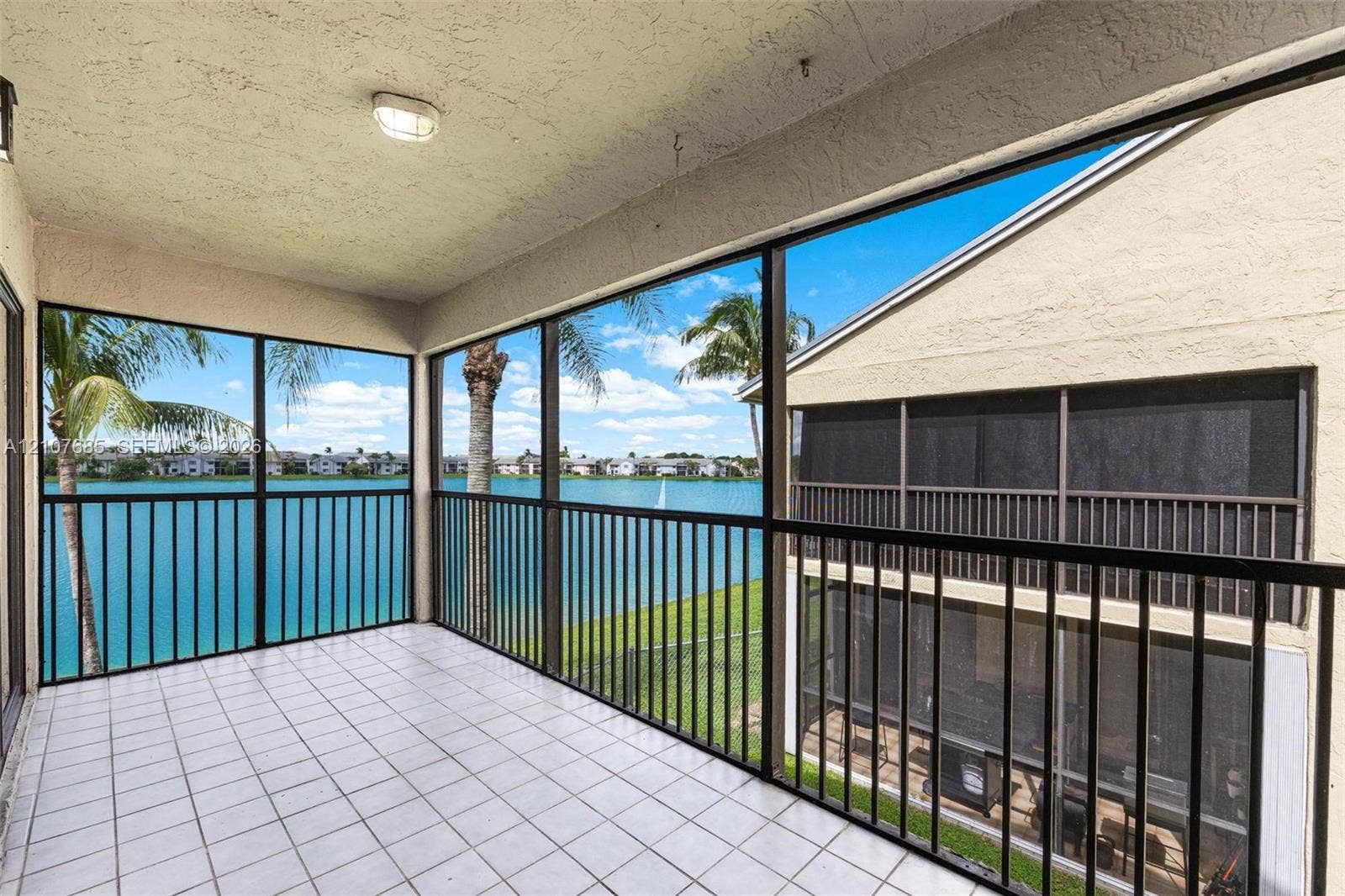 1460 Jefferson Drive, #1460L, Homestead, FL 33034 Screened-in balcony featuring tile flooring, metal railings, and stucco exterior walls