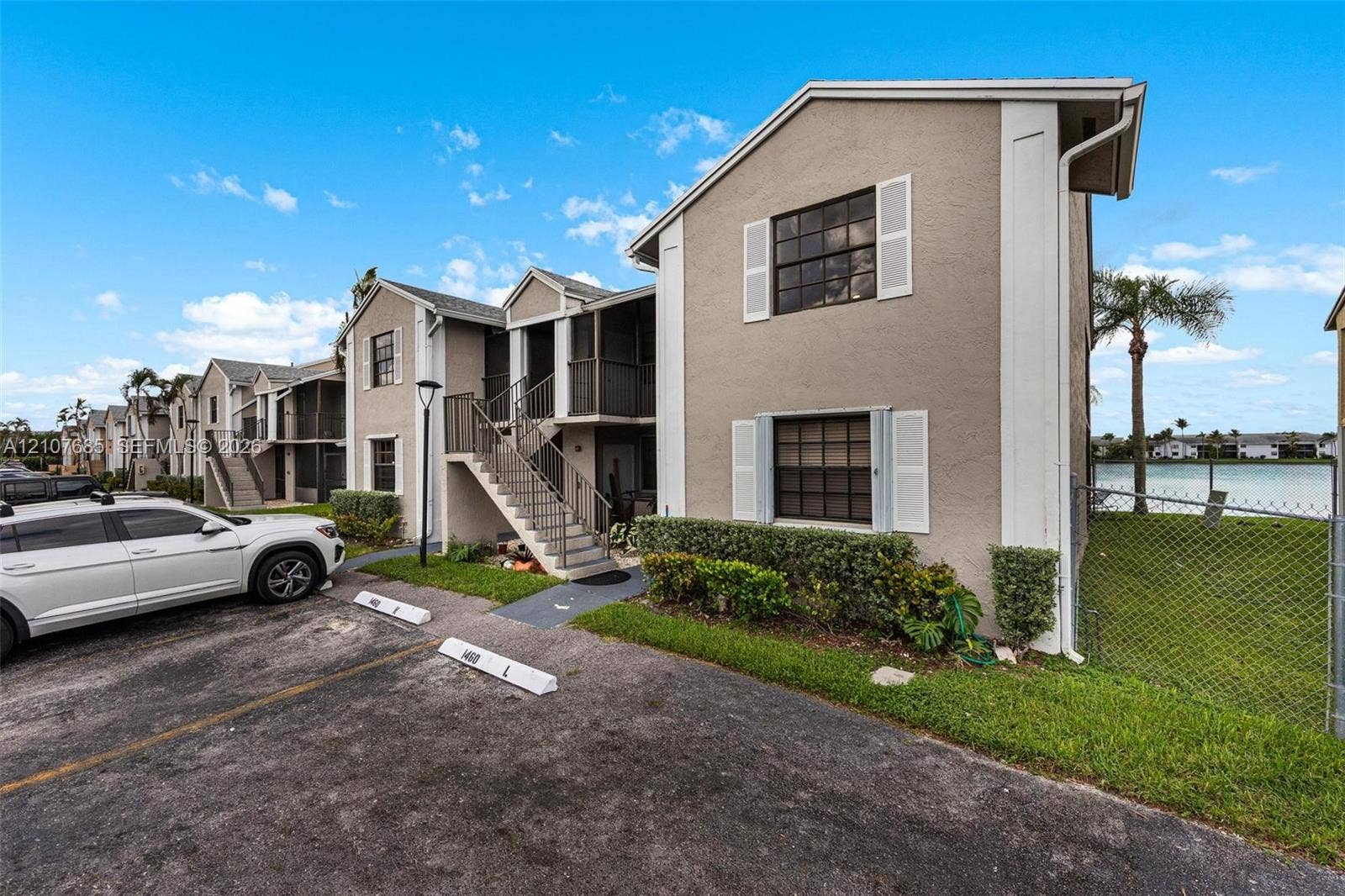 1460 Jefferson Drive, #1460L, Homestead, FL 33034 Multi-level building exterior featuring stucco siding, screened balconies, metal staircases, and grid-patterned windows
