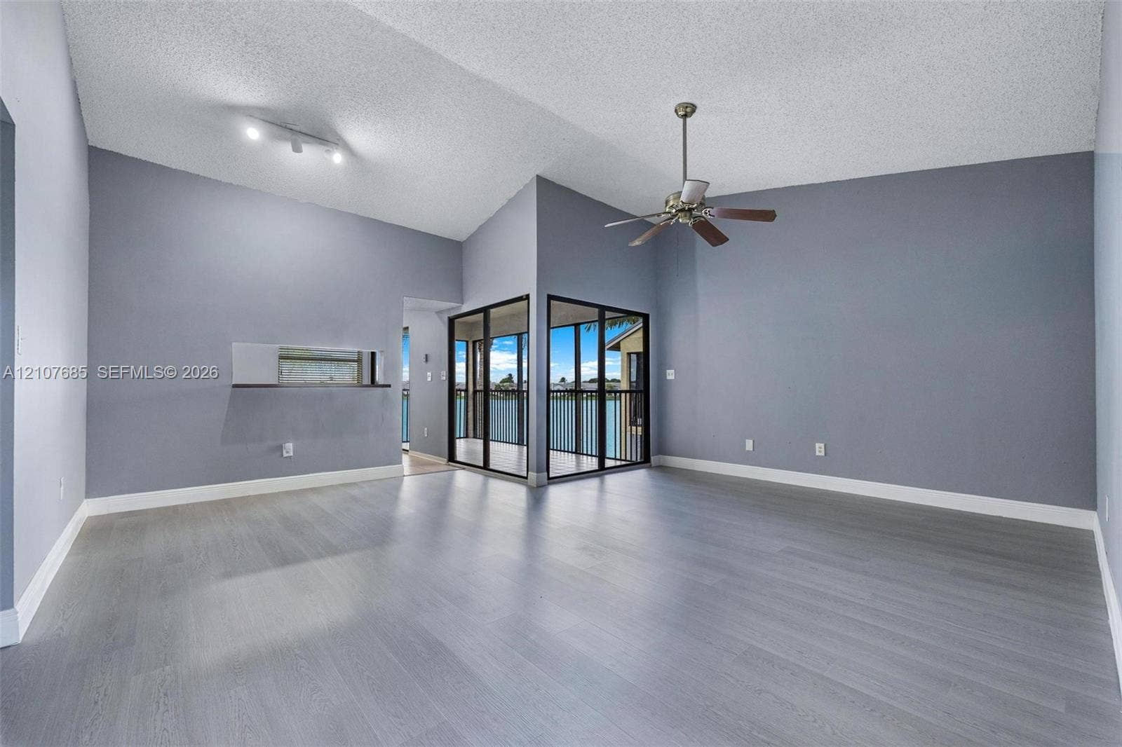 1460 Jefferson Drive, #1460L, Homestead, FL 33034 Vaulted ceilings, wood-finish flooring, ceiling fan, pass-through wall opening, and floor-to-ceiling glass enclosure