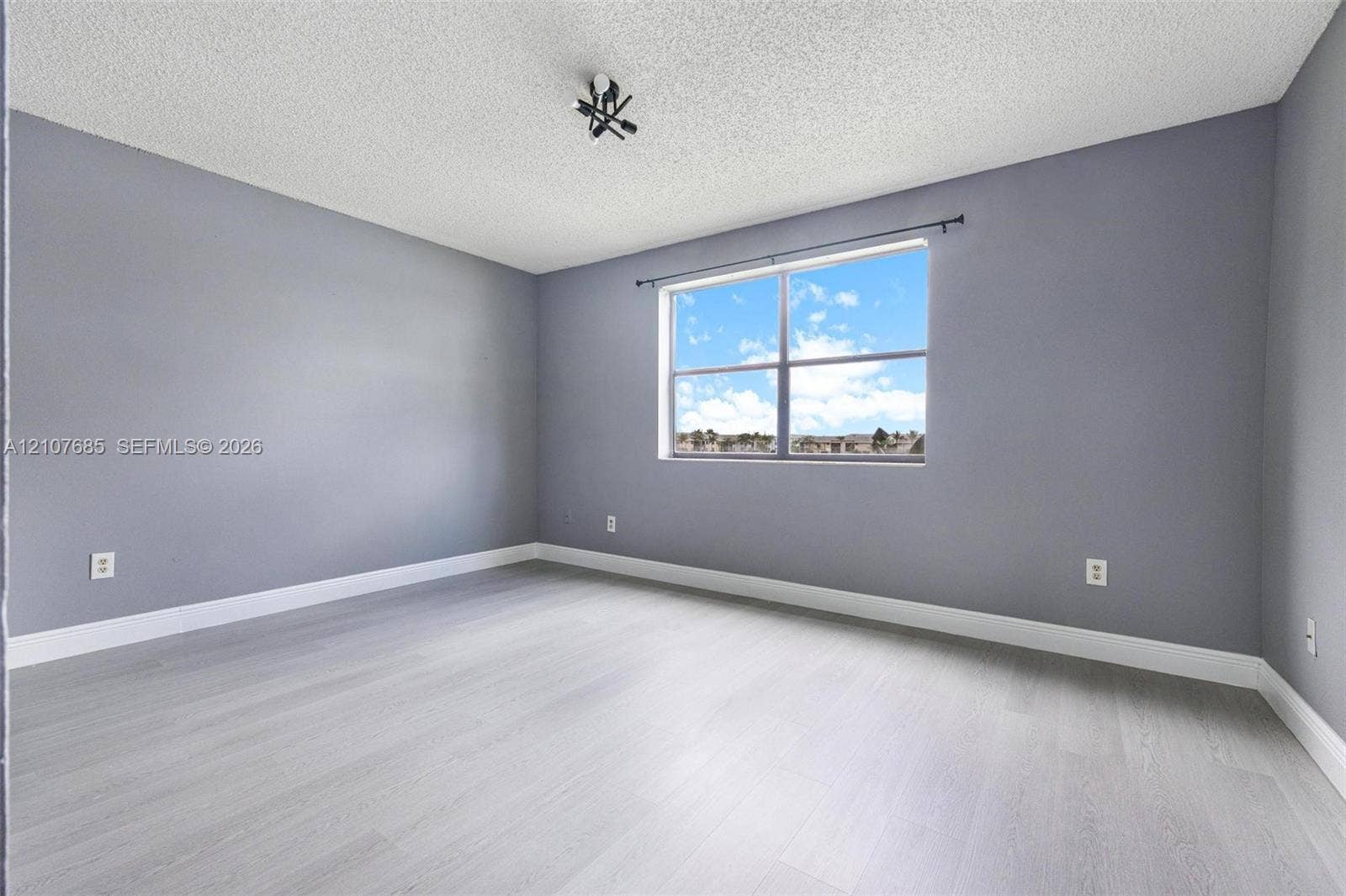 1460 Jefferson Drive, #1460L, Homestead, FL 33034 Room featuring wood-finish flooring, neutral-toned walls, and a multi-pane window with a curtain rod
