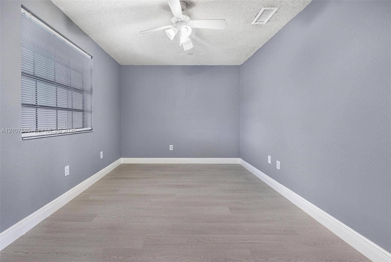 1460 Jefferson Drive, #1460L, Homestead, FL 33034 Neutral wall palette featuring wood-finish flooring, a ceiling-mounted fan with integrated light fixture, and horizontal window blinds