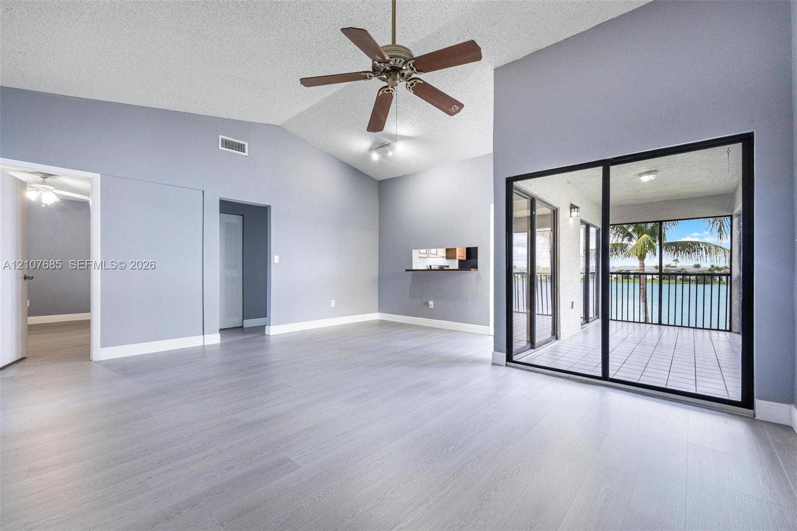 1460 Jefferson Drive, #1460L, Homestead, FL 33034 Vaulted ceilings, wood-finish flooring, ceiling fan, and floor-to-ceiling sliding glass doors leading to a screened lanai with water scenery