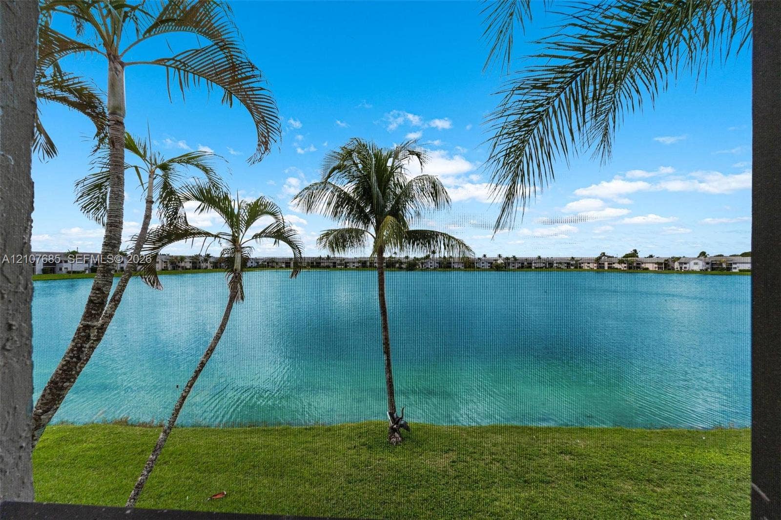 1460 Jefferson Drive, #1460L, Homestead, FL 33034 Waterfront property featuring a manicured grass lawn and mature palm trees