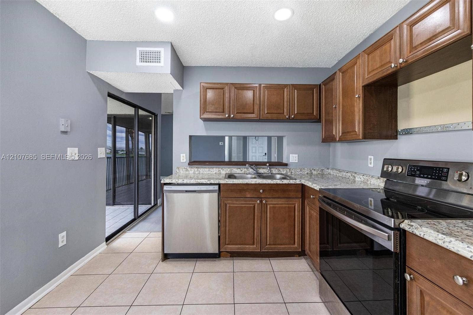 1460 Jefferson Drive, #1460L, Homestead, FL 33034 Kitchen featuring medium-tone wood cabinetry, stone-patterned countertops, stainless steel appliances, recessed ceiling lighting, and ceramic tile flooring