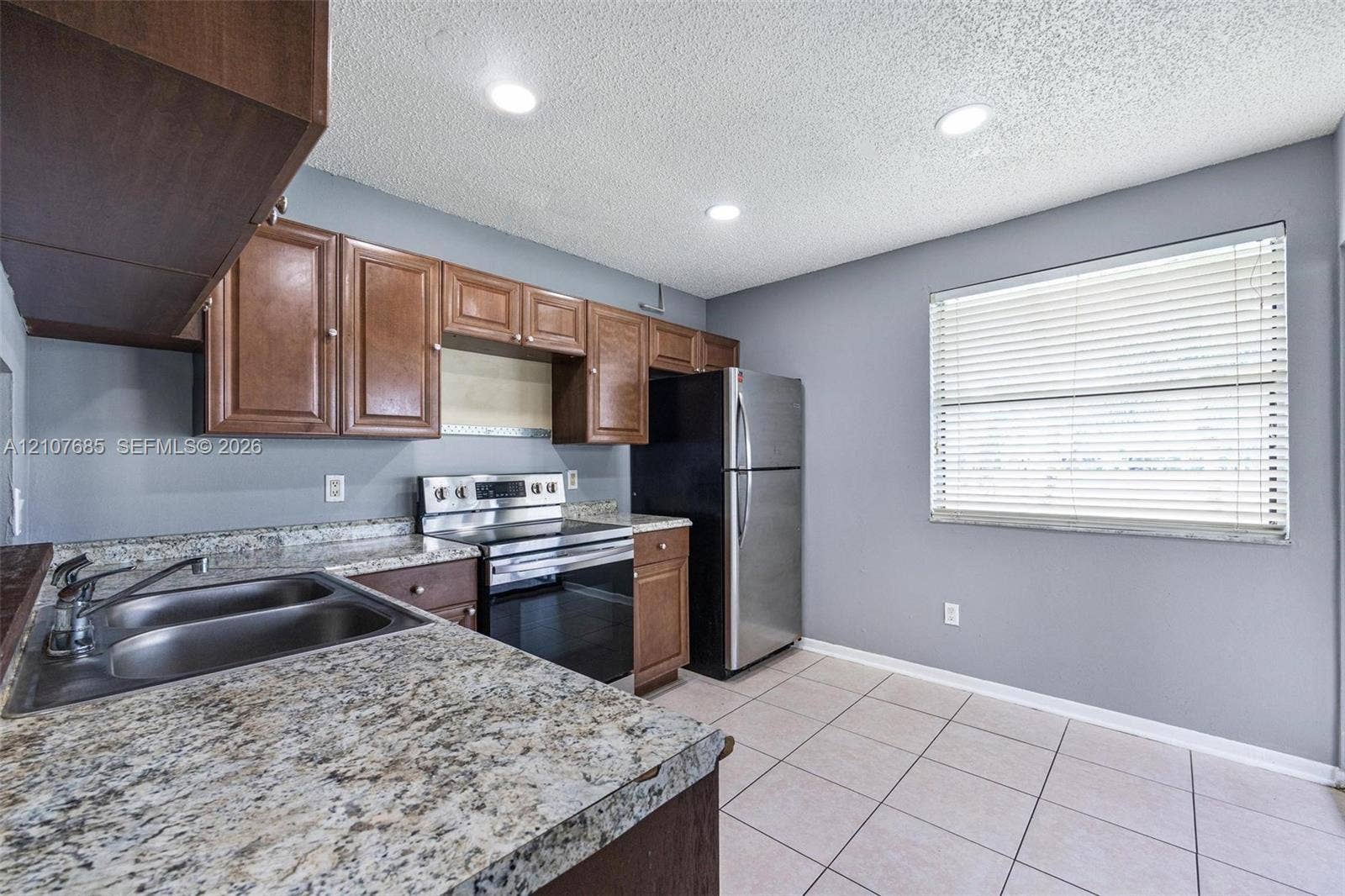 1460 Jefferson Drive, #1460L, Homestead, FL 33034 Kitchen featuring wood cabinetry, stone-finish countertops, dual-basin stainless steel sink, stainless steel range, and tile flooring