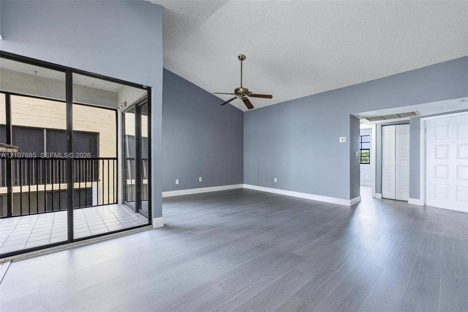 1460 Jefferson Drive, #1460L, Homestead, FL 33034 Vaulted ceilings, wood-finish flooring, ceiling fan, and sliding glass doors with direct access to a private balcony