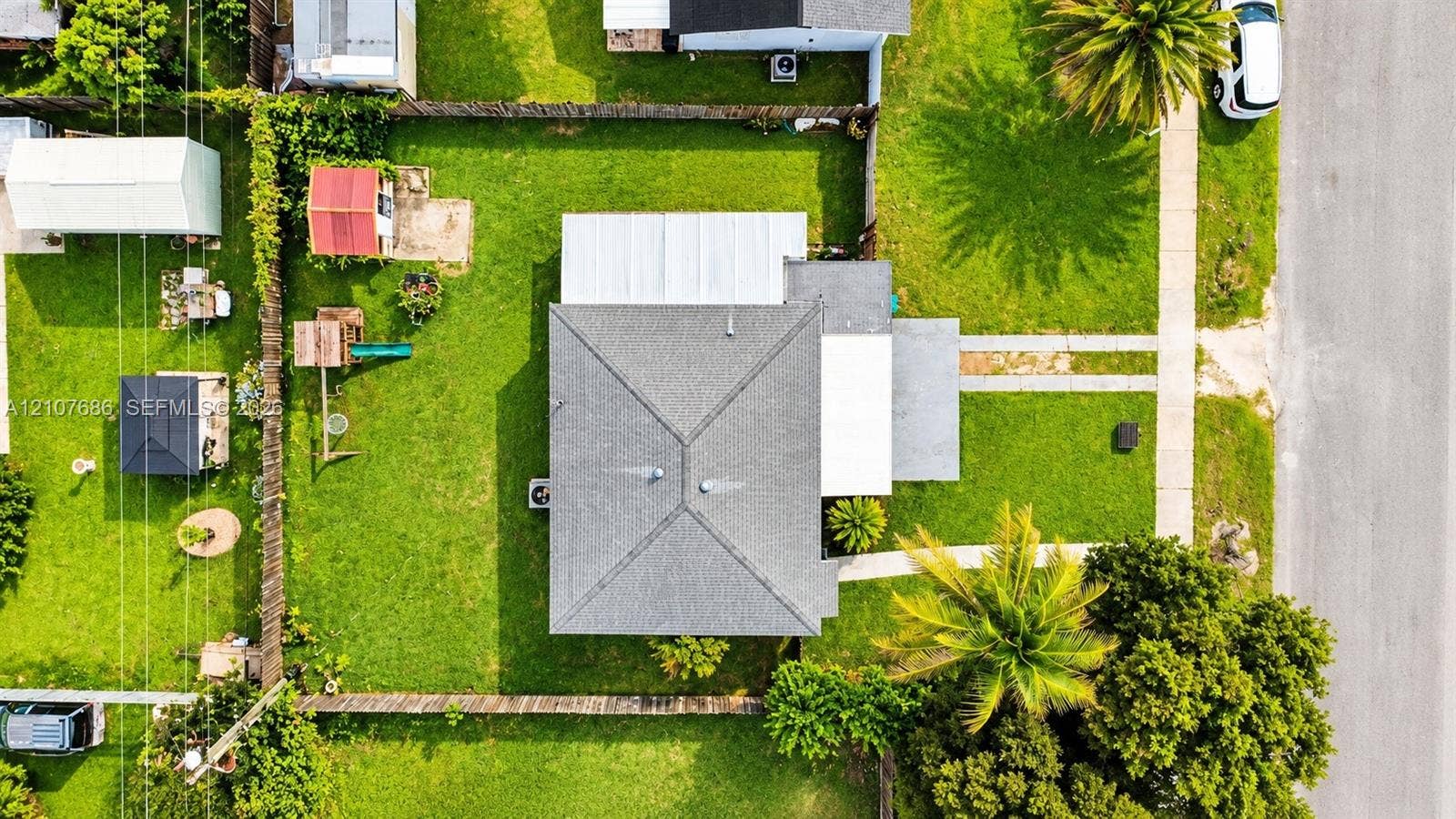 9760 Jamaica Drive, Cutler Bay, FL 33189 Aerial perspective featuring a lot with a fenced backyard, grass lawn, concrete driveway, and mature trees
