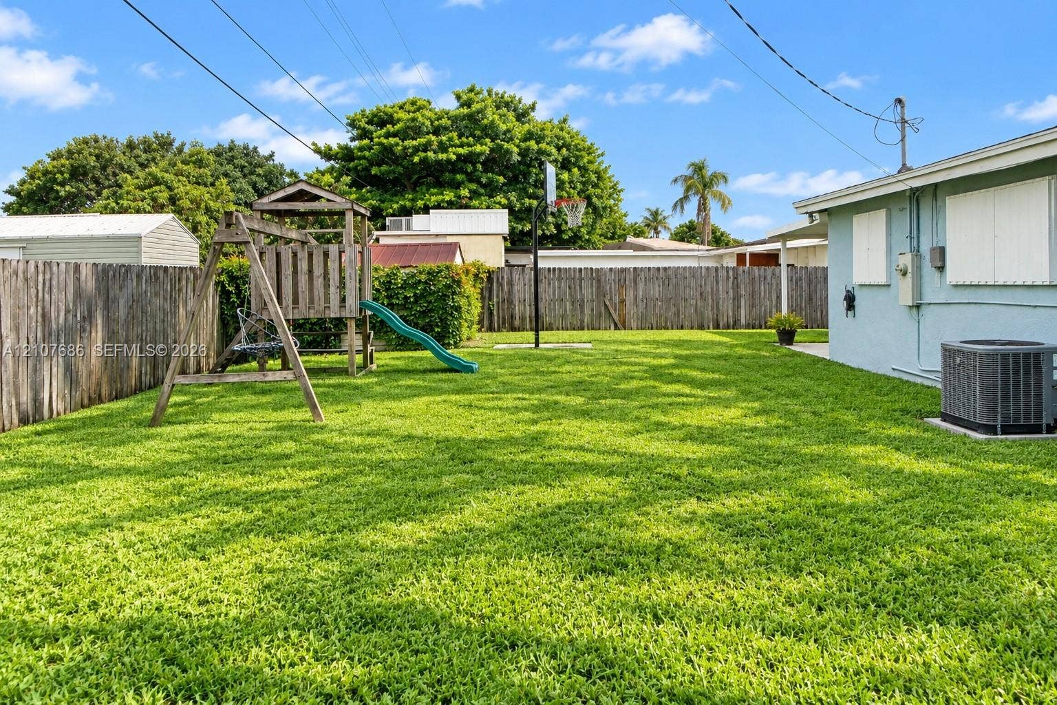 9760 Jamaica Drive, Cutler Bay, FL 33189 Expansive backyard featuring a fenced perimeter, manicured lawn, and exterior wall-mounted shutter panels