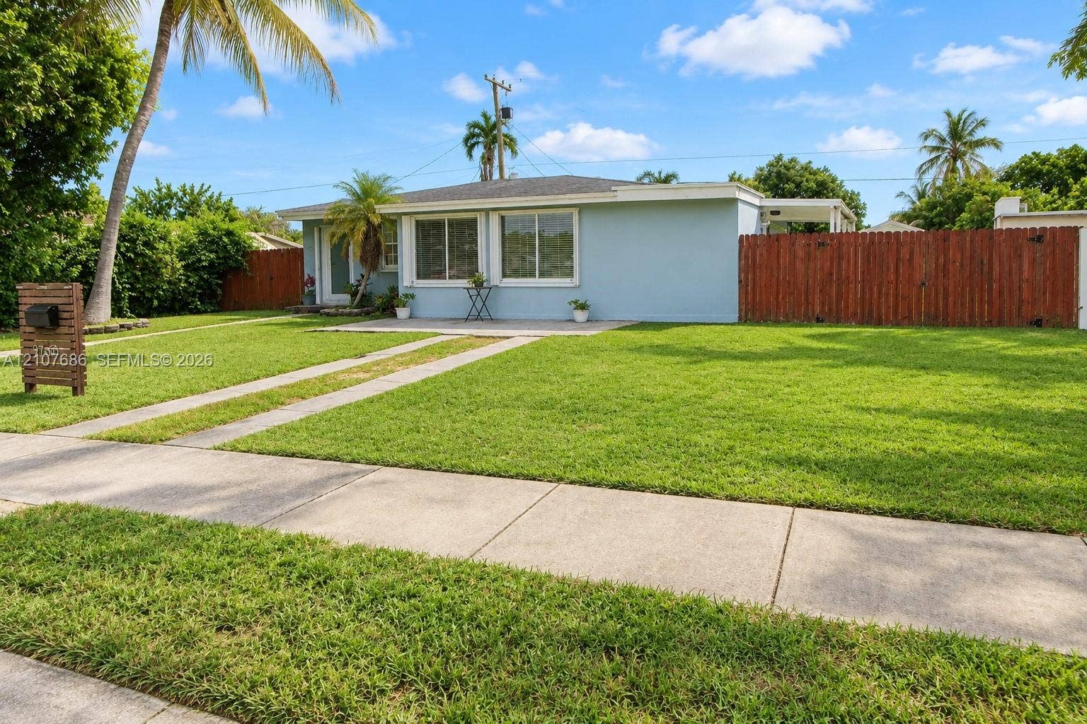 9760 Jamaica Drive, Cutler Bay, FL 33189 Single-story residence featuring light-toned exterior siding, a paved concrete driveway, a front patio area, and a wood privacy fence